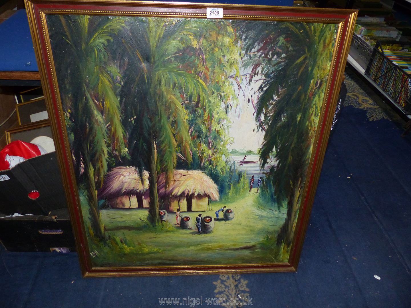 A large framed oil on board depicting an African village,