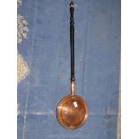 A copper bed warming pan with ebonised handle.