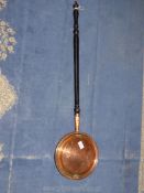 A copper bed warming pan with ebonised handle.