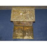 A wooden lidded brass coal box on wheels decorated with relief tavern and country scenes,