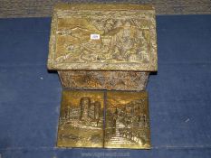 A wooden lidded brass coal box on wheels decorated with relief tavern and country scenes,