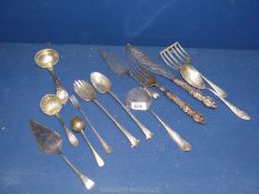 A plated set of fish servers, plated cake slices, a pickle fork, plated ladles, a tea acorn,