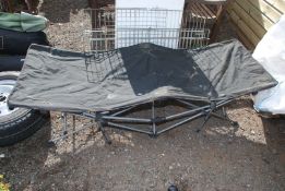 A fold out camp bed and a small dog run.