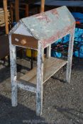 A painted wooden saddle rack 43" high x 42" long with a drawer and a lower shelf.