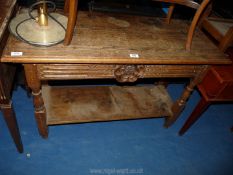 A side table with ornately carved front having lower shelf.