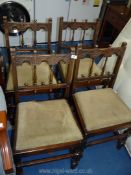 Four Ercol dining chairs with carved detail and green upholstered slot in seats.