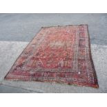 A terracotta and maroon ground bordered, patterned and fringed rug. 114'' long x 80''.