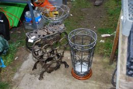 A metal wine rack in the shape of grape bunch, umbrella stand and plant pot holder.