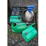 Two petrol fuel cans and a diesel fuel can together with watering can and a sprayer.