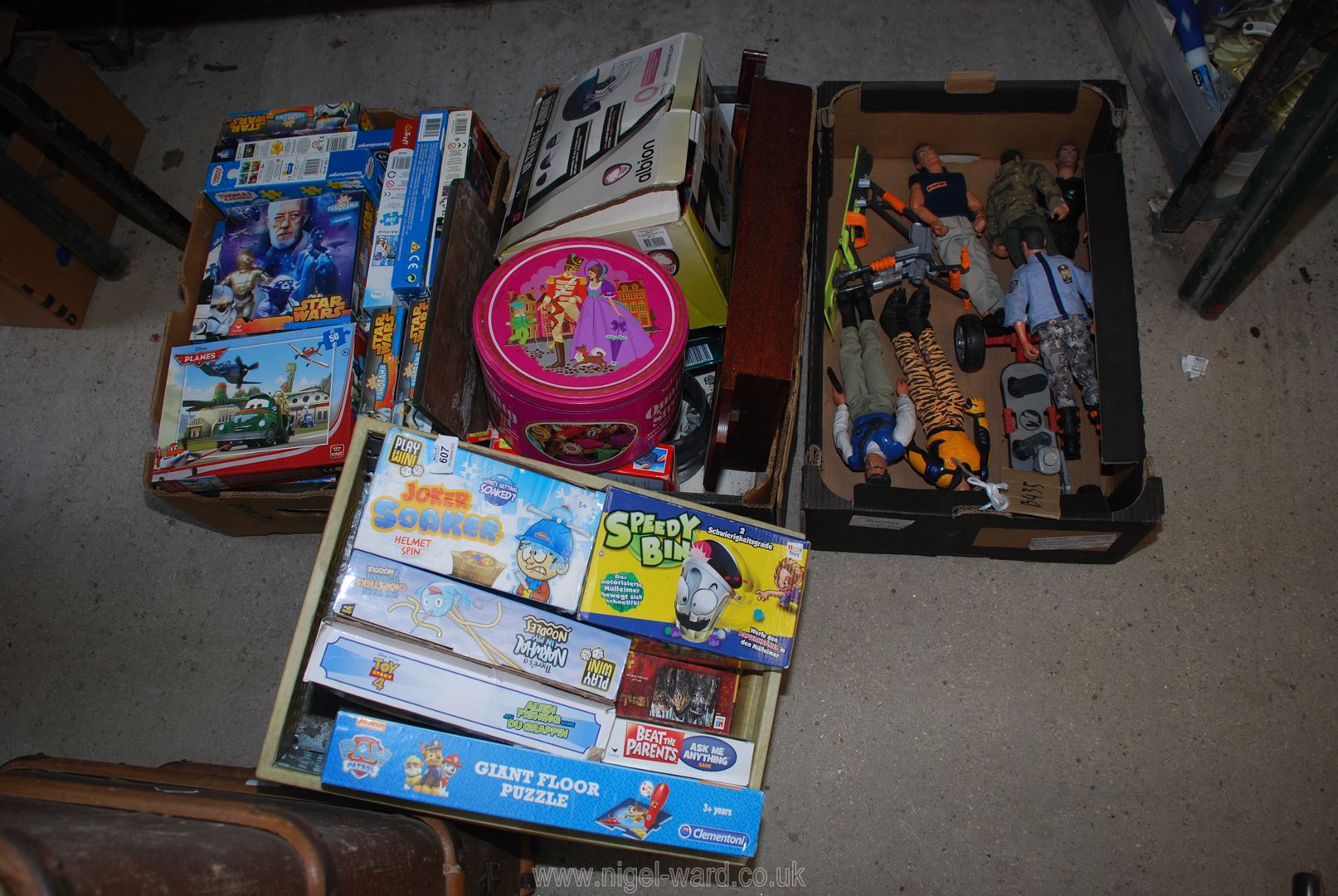 A box of games, giant puzzles and action man figures.