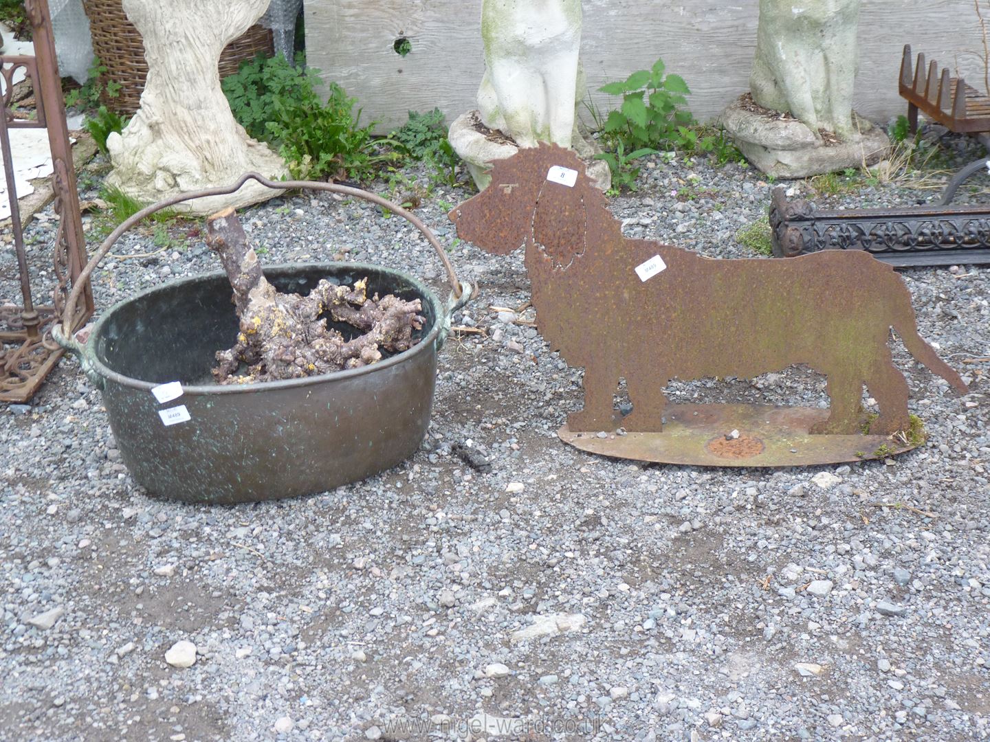 An iron cut-out figure of a Dog and an oval brass cooking pot with iron swing handle.