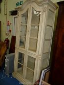 A cream painted display Cabinet with glazed panel doors and shelves,