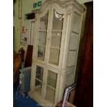 A cream painted display Cabinet with glazed panel doors and shelves,