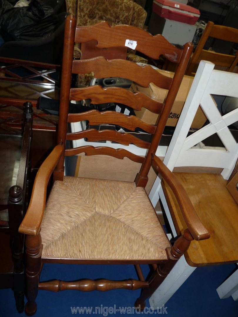 A light wood ladder back rush seated arm chair.