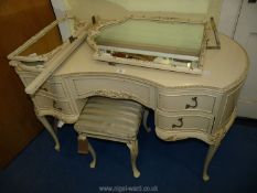 A cream painted kidney shaped dressing table with triptych mirror and stool.