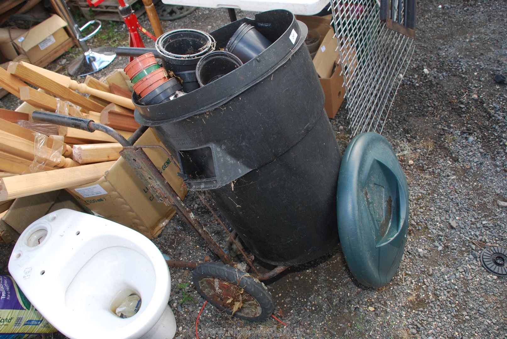 A wheel carrier (in need of attention), black bin and plant pots.