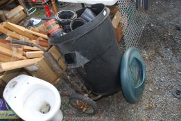 A wheel carrier (in need of attention), black bin and plant pots.