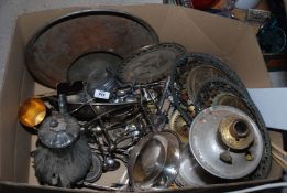 A large box containing old pewter, large oil lamp, oriental metal trays and plates, cutlery etc.