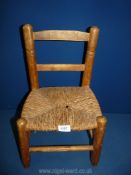 A child's wooden and rush seated chair, 18 1/2" high.