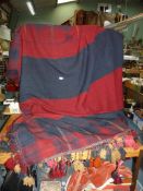 A large navy and terracotta blanket with hand stitched tassels and beads along the end,