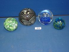 Four glass paperweights including a Langham England in green swirls.