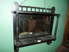 An ebonised wall hanging Mirror with two shelves having carved detail,