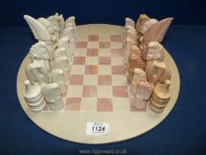 A complete stone Chess set in pink and cream depicting figures (chip to one pink pawn).