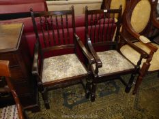 A pair of dark Oak framed Elbow Chairs having turned spindle backs,