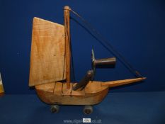 A home-made wooden model of a Ship with a wooden sail having 4 roller skate wheels,