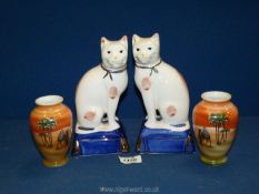 A pair of Staffordshire seated cats on blue and gilt cushions,