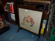 A dark wood framed tapestry fire screen depicting flowers, 29" tall.
