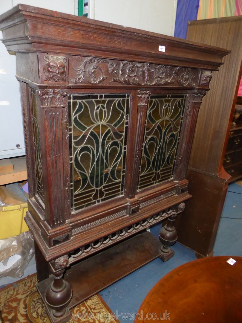 A most unusual Oak Cabinet on stand having a pair of opposing intricately coloured leaded glazed