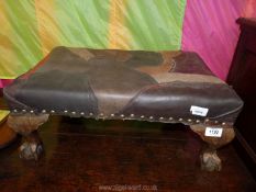 A low Footstool standing on ball and claw legs and having an unusual patchwork leather top,