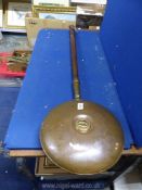 A copper bed warming pan with twist open lid.