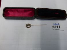 A cased stick Pin in the shape of a horse shoe with three rubies and four pearls.