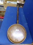 A copper bed warming pan with wooden handle, some dents.