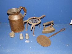 A three legged trivet, a large copper jug, brass iron and a skimmer.