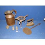 A three legged trivet, a large copper jug, brass iron and a skimmer.