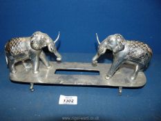 A white metal Desk stand with two elephants at either end, possibly missing central piece,
