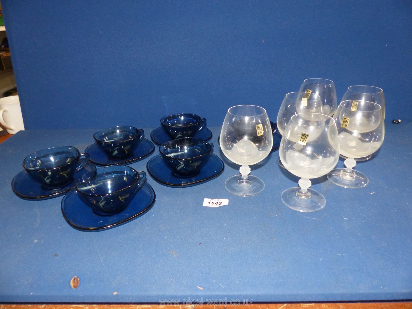 A set of blue glass cups and saucers (6) and a set of 'Lily' Brandy glasses (6).