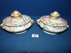 A pair of oriental dishes with lids with Famille rose borders around panels of domestic scenes,