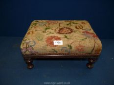 A footstool with needlepoint covered top.