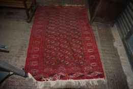 A burgundy rug with border pattern and fringing, some fading, 76" x 46".
