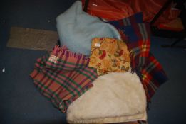 A quantity of woollen blankets in various shades, blue, multicoloured and a white synthetic throw.