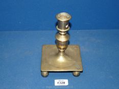 An early 17th century Spanish square base brass candlestick inscribed and with a date now obscured