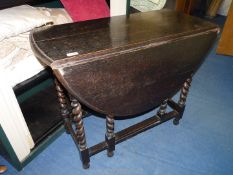 A dark Oak gateleg dropleaf Table standing on mirrored twist supports,