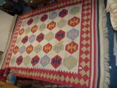 A Kilim rug in geometric pattern with red border and fringing, 95" x 65".