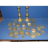 A quantity of horse brasses, two having china/ceramic centre, plus a pair of brass candlesticks.