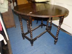 A dark Oak gateleg dropleaf Table standing on mirrored twist supports,