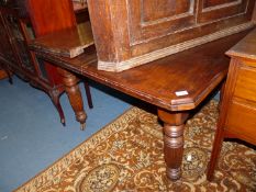 An Edwardian Mahogany wind-out Dining Table standing on turned and reeded legs,